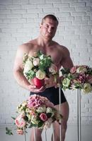 atleta masculino sexy com buquês de flores em fundo branco foto