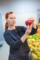 garota caucasiana comprando produtos alimentares de legumes frescos no mercado foto