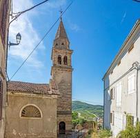 vista sobre a estrada histórica de paralelepípedos para motovun com igreja evangélica durante o dia foto