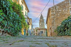 vista sobre a estrada histórica de paralelepípedos para motovun com igreja evangélica durante o dia foto