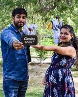 casal indiano posando para ensaio de maternidade. o casal está posando em um gramado com grama verde e a mulher está vacilando sua barriga no jardim lodhi em nova delhi, índia foto