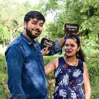 casal indiano posando para ensaio de maternidade. o casal está posando em um gramado com grama verde e a mulher está vacilando sua barriga no jardim lodhi em nova delhi, índia foto