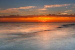 padrões na areia do mar ao pôr do sol foto