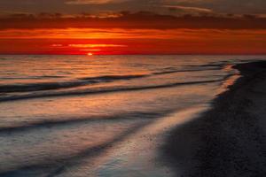 padrões na areia do mar ao pôr do sol foto