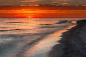 padrões na areia do mar ao pôr do sol foto