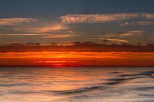 padrões na areia do mar ao pôr do sol foto