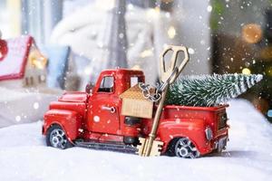 carro retrô vermelho com uma árvore de natal decora com a chave da casa na caminhonete para o natal. compra de uma casa, mudança, hipoteca, empréstimo, imóveis, clima festivo, ano novo foto