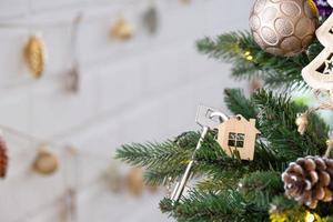 a chave da casa com um chaveiro está pendurada na árvore de natal. um presente para o ano novo, natal. construir, projetar, projetar, mudar de casa, hipotecar, alugar e comprar imóveis. espaço de cópia foto