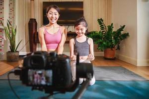 treinador de ioga e garota filmando aula online de ioga em vídeo. estilo de vida saudável - tecnologia em casa foto
