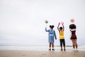 a parte de trás de um grupo de crianças afro-americanas na praia. conceito etnicamente diverso foto