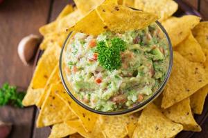 abacate guacamole, limão, tomate, cebola e coentro, servido com nachos - lanche mexicano tradicional foto