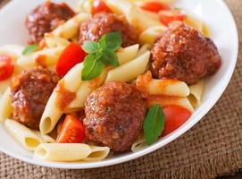 macarrão penne com almôndegas em molho de tomate em uma tigela branca foto