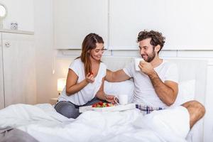 café da manhã romântico na cama homem se prepara para sua mulher, ela estava muito feliz, jovem casal lindo na cama tomando café da manhã e café na cama foto