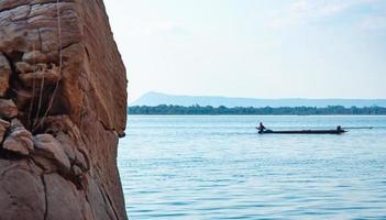 pedras à beira do lago, fundo desfocado, pescadores em barcos. cenário natural que dá uma sensação de força foto