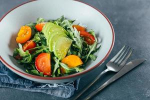 salada vegana saudável com tomate, rúcula, abacate e gergelim. menu de dieta vegana. foto
