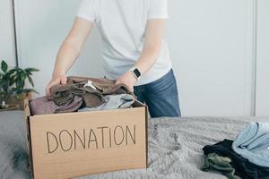 caixa de doação com roupas. mulher preparando roupas para doação foto