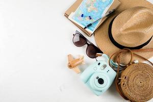 viajar plano leigo. bolsa de vime, chapéu de palha, óculos de sol, câmera e avião. vista superior, copie o espaço foto