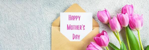 conceito de dia das mães. tulipas cor de rosa, cartão em fundo de concreto. postura plana. imagem do banner