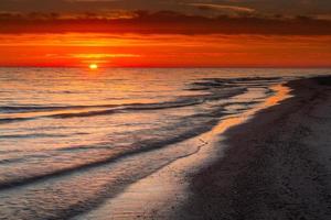 padrões na areia do mar ao pôr do sol foto