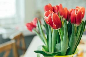 buquê fresco de tulipas vermelhas em um vaso na mesa da cozinha. estilo de vida, conceito de férias. copie o espaço.