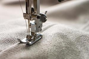 máquina de costura moderna e tecido cinza. processo de costura, feito à mão, passatempo, bricolage, negócios, reparação foto
