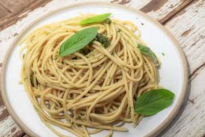 macarrão com molho pesto no prato na comida italiana de fundo de madeira. foto