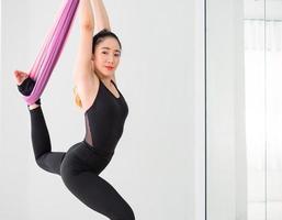 jovem bela dançarina asiática vestida de preto aquecendo e alongando antes da dança aérea no estúdio. foto