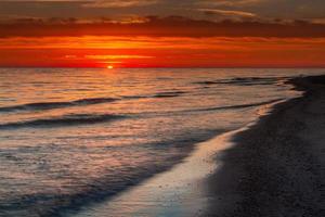 padrões na areia do mar ao pôr do sol foto