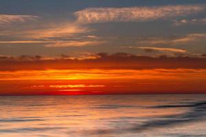 padrões na areia do mar ao pôr do sol foto