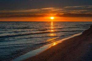 padrões na areia do mar ao pôr do sol foto