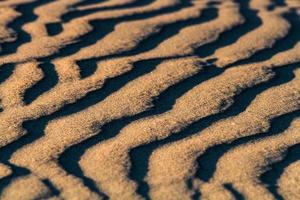 padrões na areia do mar ao pôr do sol foto