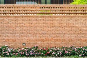 o pano de fundo da parede de tijolos com rosa - flor branca na parte inferior para história de fundo de combinação de arquitetura e natureza. foto