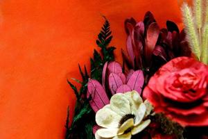 closeup e colheita decorativa colorida de flores artificiais secas e de papel sobre fundo vermelho. foto