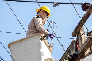 closeup eletricistas trabalhando no teleférico para reparar a linha de energia sob o fundo do céu azul claro. foto