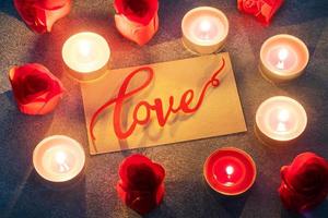 rosas vermelhas e velas acesas, close-up, cartão romântico. conceito de dia dos namorados. foto