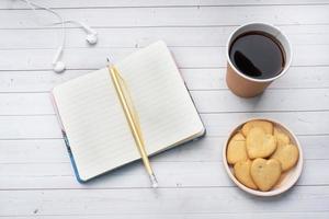 café preto em um copo de papel e biscoitos em forma de coração em um fundo branco. espaço de cópia plana leiga, vista superior. foto