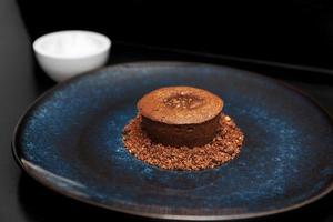 sobremesa de vulcão de chocolate, em um prato azul ao lado de sorvete em um fundo preto foto
