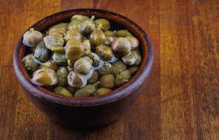 tigela de barro com alcaparras fica em uma mesa de madeira. foto