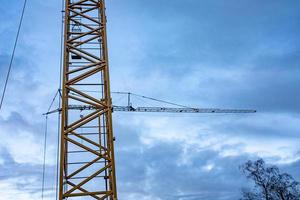 guindaste de construção muito alto sobre canteiro de obras foto