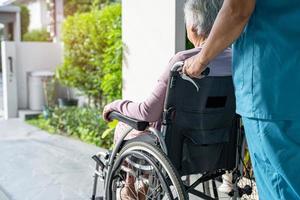 cuidador, ajuda e cuidado paciente idoso asiático ou idosa senhora sentada em uma cadeira de rodas na rampa de um hospital de enfermagem, conceito médico forte e saudável foto