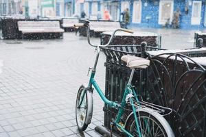 bicicleta retrô à moda antiga. rua da cidade com a primeira neve, queda de neve, foco seletivo, fundo de inverno foto