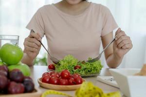comida saudável. as mulheres planejam dietas para uma forma esbelta e saudável. mulher comendo legumes, salada e tomate
