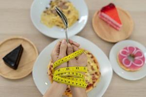 fita métrica em torno dos braços das mulheres. pare de comer gorduras trans, espaguete, rosquinhas, waffles e doces. perder peso para uma boa saúde. conceito de dieta de vista superior foto