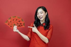 mulher asiática segurando o envelope da fortuna de dinheiro vermelho abençoando a palavra chinesa, o que significa que você pode ter muita sorte e grande lucro isolado em fundo vermelho para o conceito de celebração do ano novo chinês foto