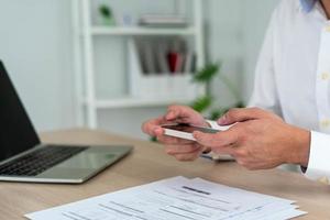 um homem de negócios usa seu telefone para digitalizar um código de barras para pagar sua fatura mensal de cartão de crédito após receber uma fatura. conceito de pagamento de contas on-line foto