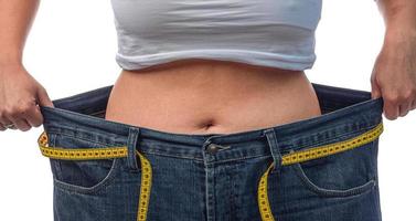 close-up de uma mulher medindo o tamanho da cintura com fita métrica. foto