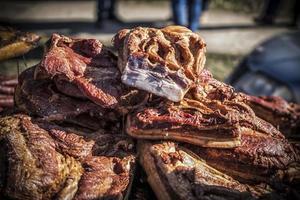 uma barraca ao ar livre com pedaços de bacon e carne seca sendo vendidos foto