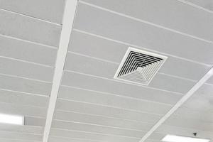 Condicionador de ar tipo cassete montado no teto e luz de lâmpada moderna no teto branco. Condicionador de ar de duto para casa, hall ou escritório. foto