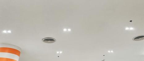 Condicionador de ar tipo cassete montado no teto e luz de lâmpada moderna no teto branco. Condicionador de ar de duto para casa, hall ou escritório.