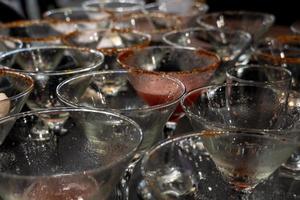 martini, dois copos com azeitonas picantes. coquetel alcoólico em um fundo azul foto